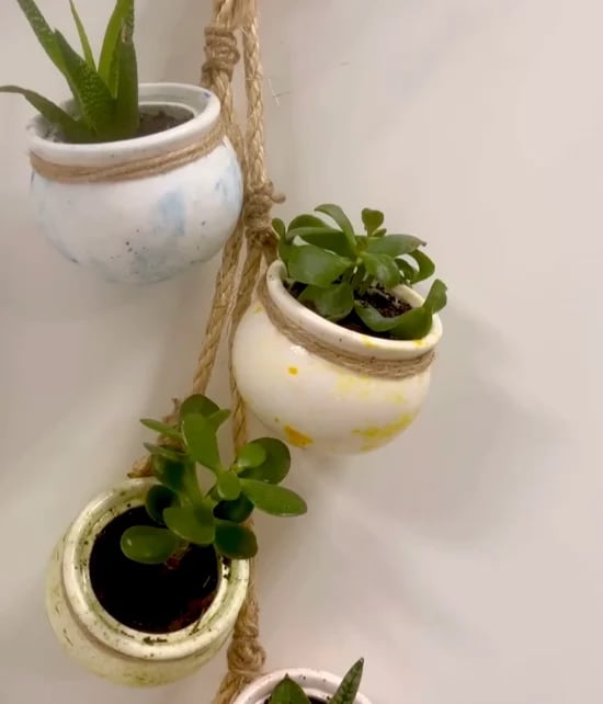 Trzy małe ceramiczne wiszące doniczki z sukulentami na sznurku jutowym